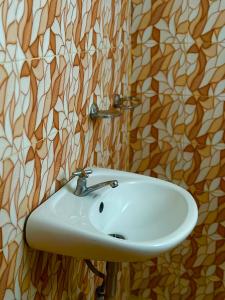 a white sink in a bathroom with wallpaper at Rozay Travellers Inn in Kabankalan