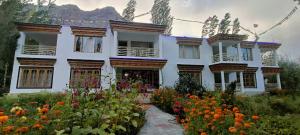 a large white house with flowers in front of it at Hotel Onpo Hunder Nubra Valley in Hundar