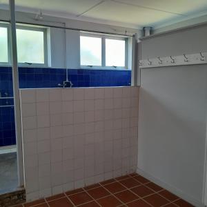a bathroom with blue and white tiled walls and windows at TRASHAVEN - Seaside Haven Backpackers in Durban