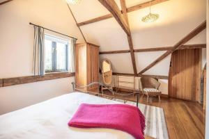 a bedroom with a bed with a pink blanket on it at South Barn, Nr Southwold in Southwold