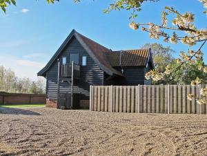 a black house with a wooden fence in front of it at South Barn, Nr Southwold in Southwold