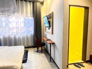 a room with a bed and a desk and a window at Ashleys Hotel in Kampala