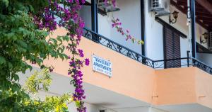 een gebouw met een balkon met paarse bloemen bij Aggeliki apartments Dassia By Hotelius in Kato Korakiana