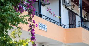 a building with a balcony with purple flowers at Aggeliki apartments Dassia By Hotelius in Kato Korakiana