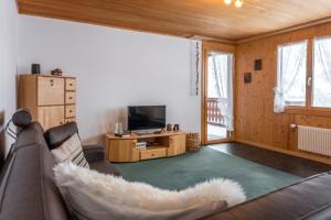ein Wohnzimmer mit einem Sofa und einem TV in der Unterkunft Apartment Obem Doregade - GRIWA RENT AG in Grindelwald