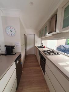 a kitchen with a clock on the wall and a counter at Townhouses by the Beach in Thirroul