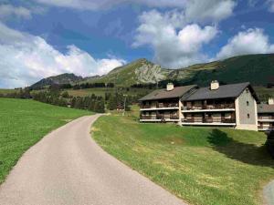 a road leading to a building with mountains in the background at Résidence A9 - Les Myosotis in Les Mosses