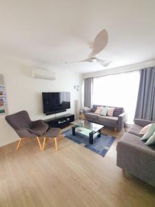 a living room with a couch and a tv at Townhouses by the Beach in Thirroul