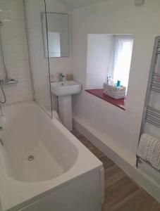 a white bathroom with a tub and a sink at Lovely 2 Bedroom Loft Apartment in Buxton in Buxton