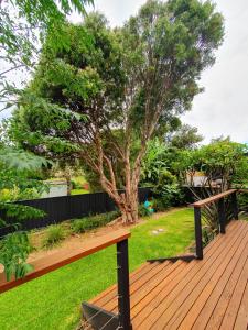 a wooden deck with a tree in a yard at Townhouses by the Beach in Thirroul