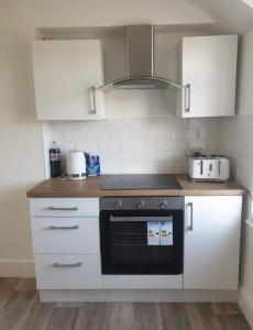 een keuken met witte kasten en een zwarte oven bij Lovely 2 Bedroom Loft Apartment in Buxton in Buxton