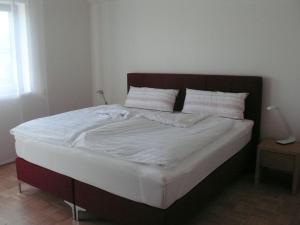 uma cama grande com lençóis brancos e almofadas em Ferienwohnung Rhönbauer Altengronau em Sinntal