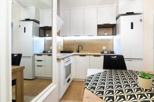 a kitchen with white cabinets and a table at Apartament z dwoma sypialniami i z miejscem postojowym in Białystok