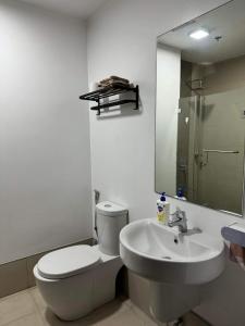 y baño con aseo, lavabo y espejo. en Abreeza Place T2 - 720 en Dávao