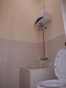 uma casa de banho com um WC com uma luz na parede em Tendy Guest House 