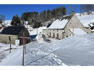 un edificio de piedra en la nieve junto a en Maison de Famille de 1823, en Chastreix