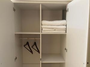 um armário com toalhas brancas e cabides em Tendy Guest House 