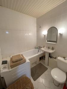 een badkamer met een bad, een toilet en een wastafel bij Cozy two-room apartment in Druskininkai