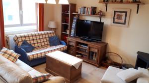 ein Wohnzimmer mit einem Sofa und einem TV in der Unterkunft El Eresma de Carmen in Hontanares de Eresma
