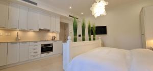 a kitchen with white cabinets and a bed in a room at Porto Montenegro Studio in Tivat