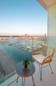 een stoel en een tafel op een balkon met uitzicht op een haven bij Silkhaus palm view 1BDR with private beach in Emaar Beachfront in Dubai