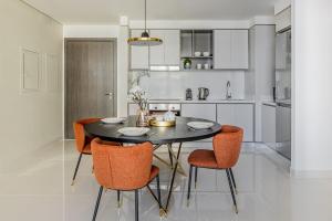 een keuken met een zwarte tafel en oranje stoelen bij Silkhaus palm view 1BDR with private beach in Emaar Beachfront in Dubai
