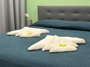 2 Betten mit weißen Handtüchern und gelben Bögen darauf in der Unterkunft Casa Marel in Lido di Ostia