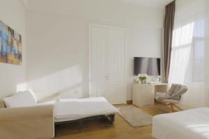a white living room with a couch and a chair at Lanterna Rooms City Center in Novi Sad