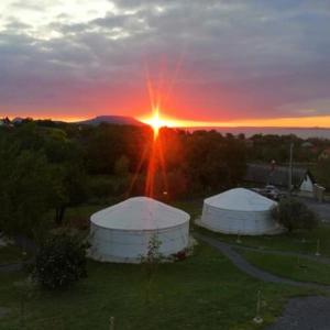 Deux tentes blanches dans un champ avec le coucher du soleil en arrière-plan dans l'établissement Jurta Hotel Balatongyörök, à Balatongyörök