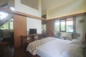 a bedroom with a bed and a desk with a television at Hotel Villa Rawa Pening Pratama by Aparian in Bandungan