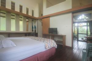 a bedroom with a large bed and a television at Hotel Villa Rawa Pening Pratama by Aparian in Bandungan