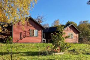 una casa rossa in un campo accanto a un cortile di Sagolikt läge med havsutsikt i Rörum på Österlen a Simrishamn