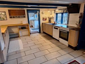 a kitchen with white appliances and a tile floor at Rødsten Gæstegård in Ulfborg