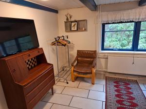 a living room with a tv and a chair at Rødsten Gæstegård in Ulfborg