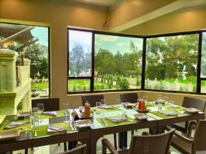 uma grande sala de jantar com uma mesa e janelas em Koru Country Club em Muhoroni