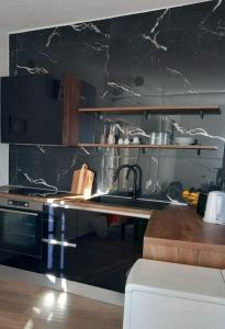 a kitchen with a sink and a black wall at Carob apartment - Balcony view of the sea & Bisevo in Komiža