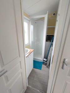 ein Badezimmer mit einer weißen Tür und einem Waschbecken in der Unterkunft Mobil-home 2 