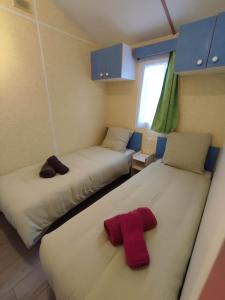 2 Betten in einem Zimmer mit einem roten Handtuch darauf in der Unterkunft Mobil-home 2 