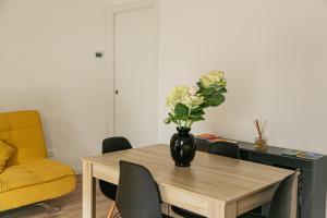 a vase of flowers on a wooden table with chairs at Alla Fiera apartment in Bergamo