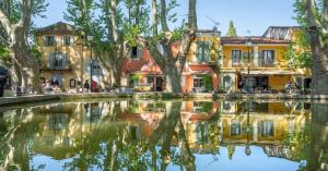 a canal in a city with houses and trees at Appartement T2 centre village in Cucuron