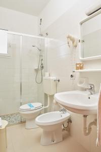 een witte badkamer met een toilet en een wastafel bij Hotel Pelikan in Lignano Sabbiadoro