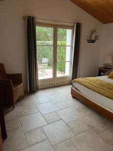1 dormitorio con 1 cama y puerta corredera de cristal en Chambres d'hôtes LES CHENES VERTS, en Le Grand Vieil