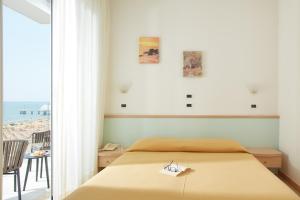 1 dormitorio con cama y vistas a la playa en Hotel Pelikan, en Lignano Sabbiadoro