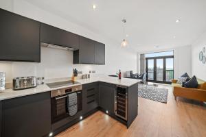 a kitchen with black and white cabinets and a living room at Retreat: Seaside Bliss In Ramsgate in Kent