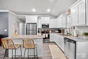 a kitchen with white cabinets and bar stools at NEW! Boho Bungalow in Bella Vista