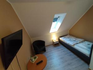 Gasthof zu den Linden 61225 في Moormerland: غرفة نوم صغيرة بها سرير وتلفزيون
