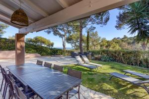 a patio with a table and chairs under a roof at SmartStay - Hyeres villa vue mer in Hyères