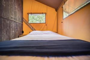 Cama en habitación pequeña con ventana en Tente lodge Jacuzzi privatif en pleine nature, en Thiel-sur-Acolin