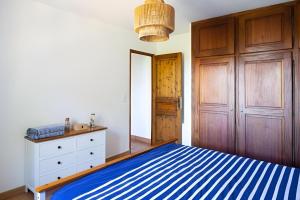 1 dormitorio con cama de rayas azul y blanco y vestidor en Mas Provençal de 120m2 en Camargue, Avec Piscine et Parking inclus, Idéal pour des vacances, en Arles