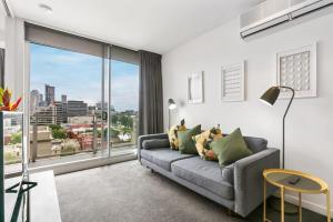 a living room with a couch and a large window at East Melb 2bed parking pet friendly in Melbourne